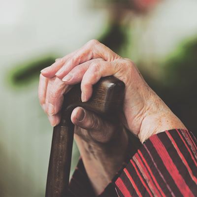 En ældre dames hænder hviler på en stok