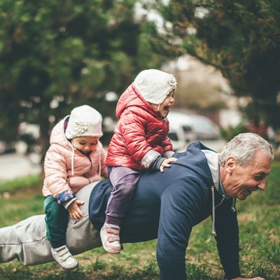 En bedstefar tager armbøjninger med sine to børnebørn på ryggen