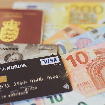 Et pas og et Banknordik betalingskort ligger ovenpå euro kontanter. 