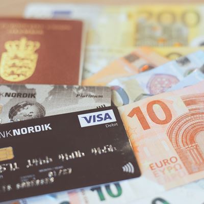 Et pass og et Banknordik betalingskort ligger ovenpå euro kontanter. 