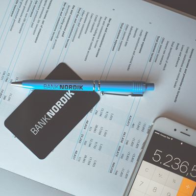 Budget med smartphone-lommeregner, kuglepen og et BankNordik kort. 