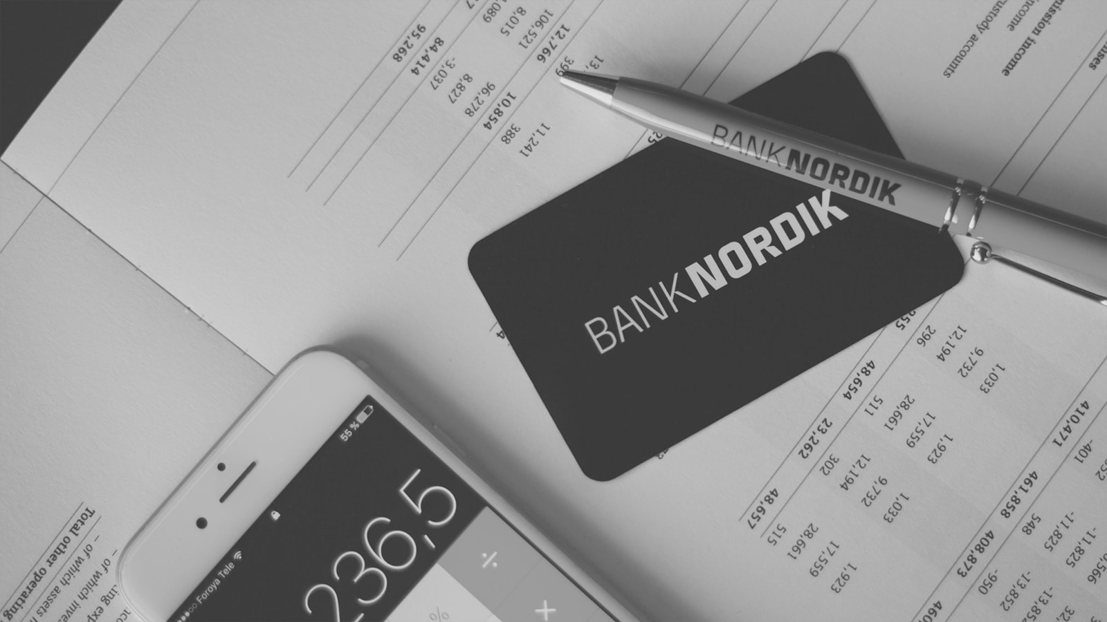 Budget med smartphone-lommeregner, kuglepen og et BankNordik kort. 