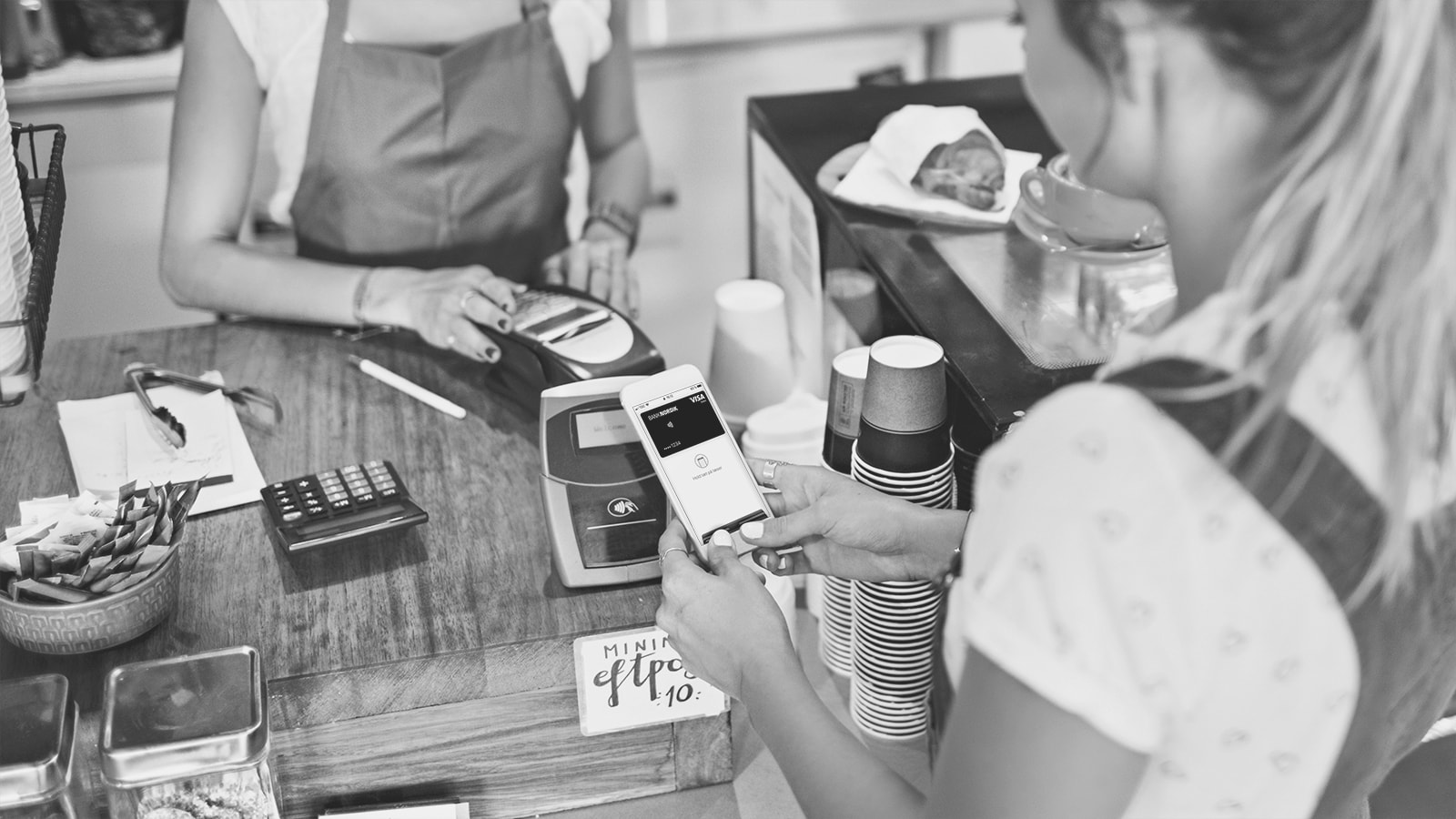 En ung kvinde betaler med Apple Pay på en café