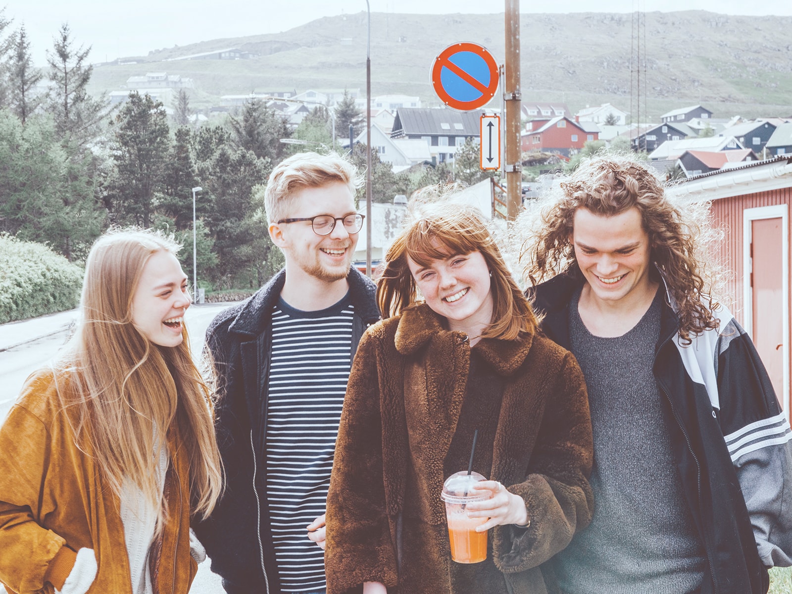 En gruppe smilende unge går tur på Færøerne