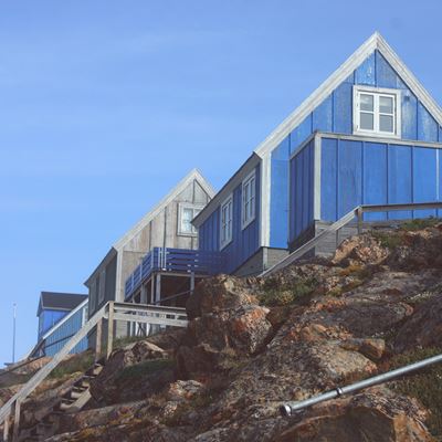 Et blåt hus med hvide vinduer på en høj bakke. 