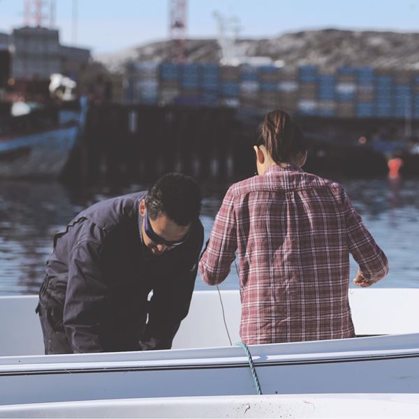 To mænd klargør båden uden for i solskinsvejr. 