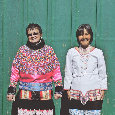 To kvinder i Grønlandsk nationaltøj med grøn baggrund. 
