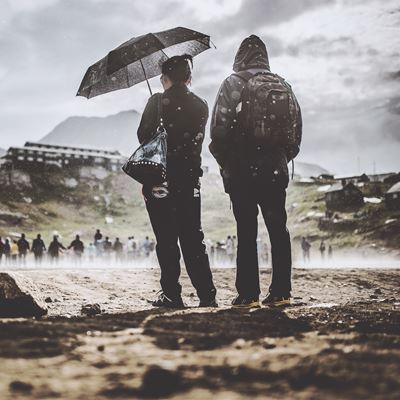 Et par står udenfor med en paraply i regnvejr. 