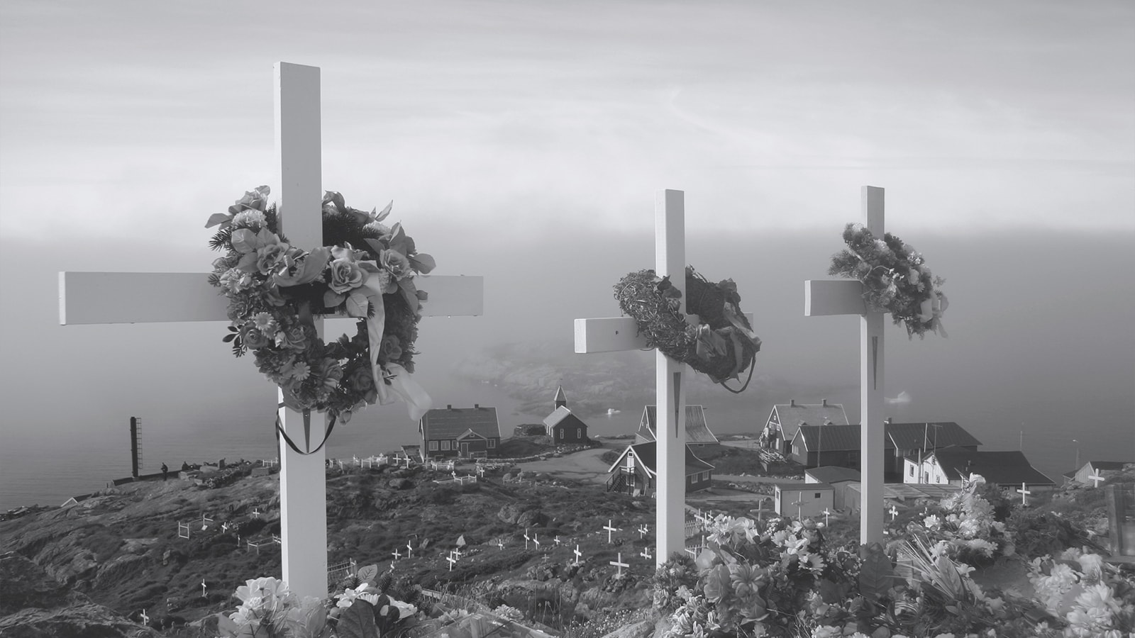 Korse i en kirkegård som ligger på en grøn bakke. 