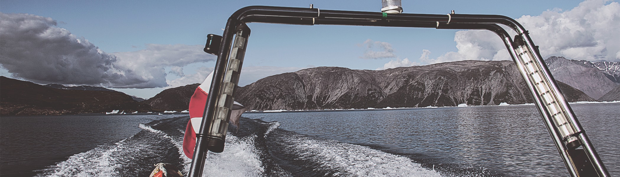 Speedbåd ligger ved vandet med udsigt over vand og bjerge. 