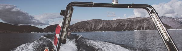 Speedbåd ligger ved vandet med udsigt over vand og bjerge. 
