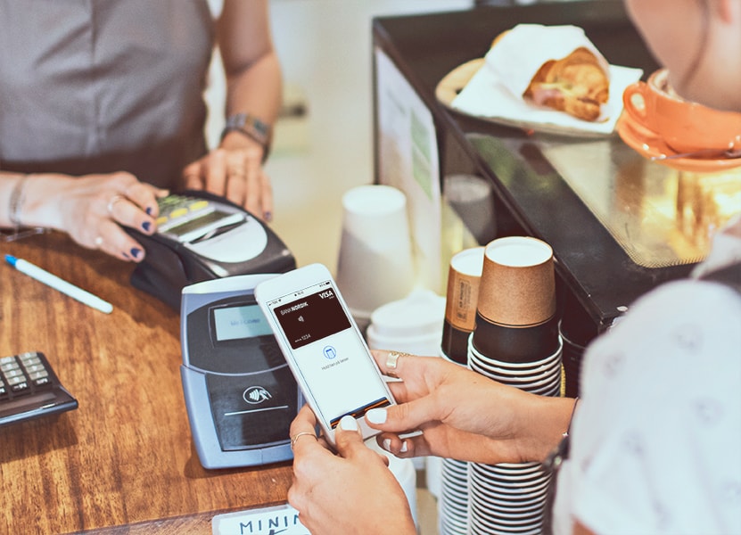 En ung kvinde betaler med Apple Pay på en café